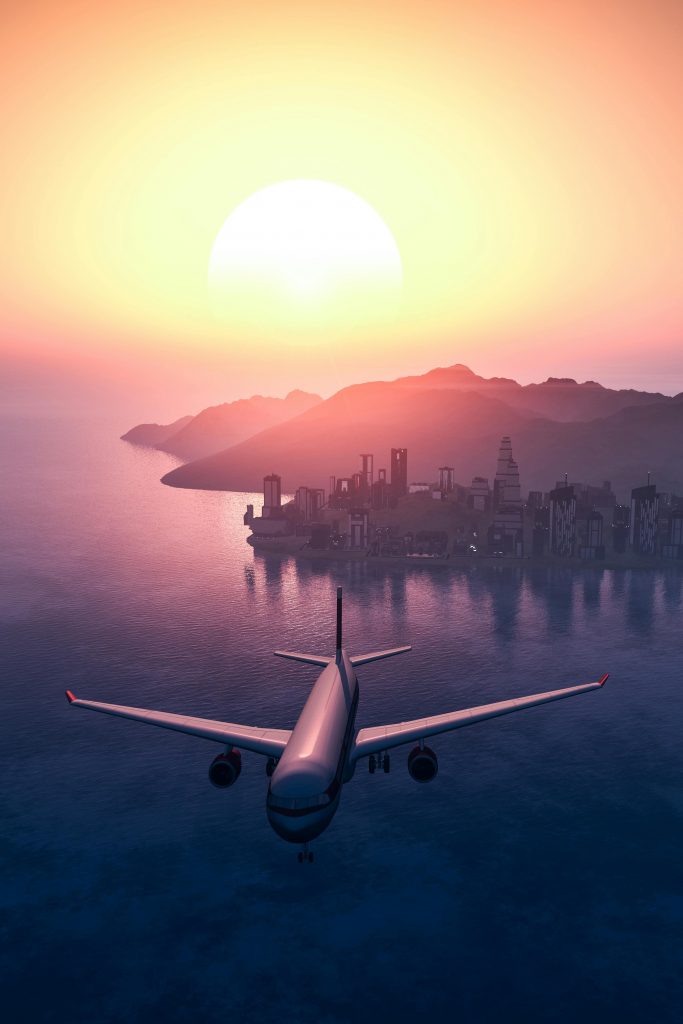 Ein Flugzeug fliegt über Gewässer. Dahinter eine hügelige Landschaft und die Abendsonne, die das Bild in Orange, Apricot und Rosa taucht.