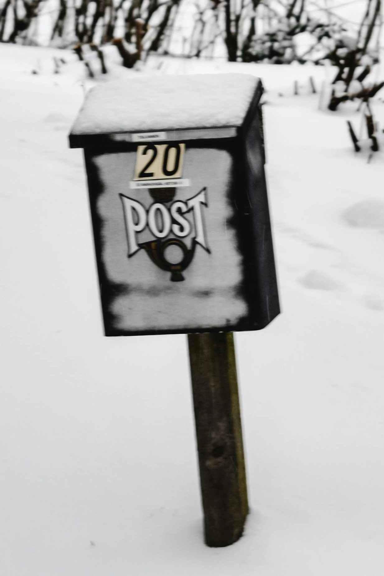 Ein kleiner verschneiter Briefkasten steht im Schnee.