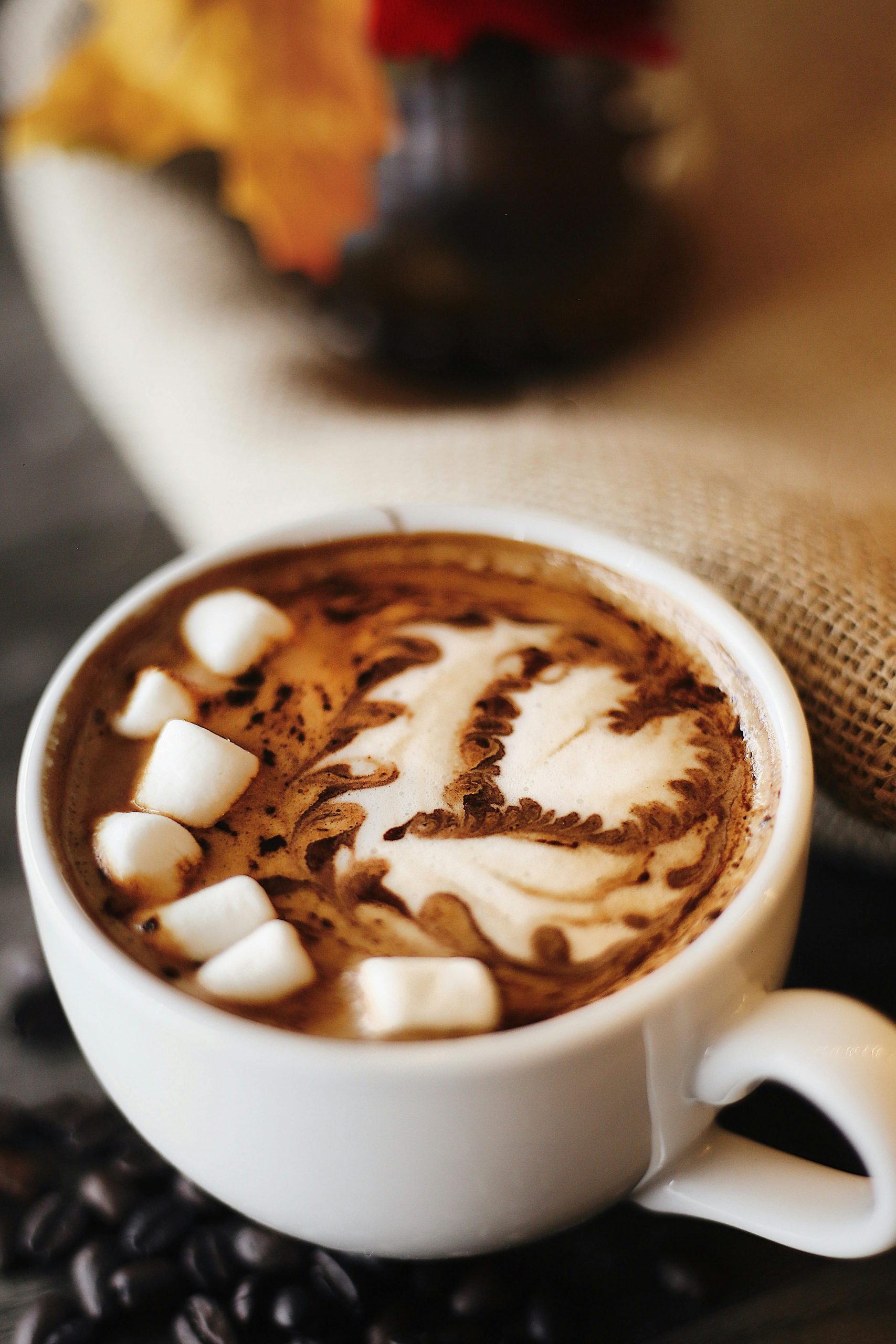 Eine weiße Kaffeetasse, auf der mit Milchschaum ein Herz gezeichnet wurde und in der kleine Marshmellows schwimmen.
