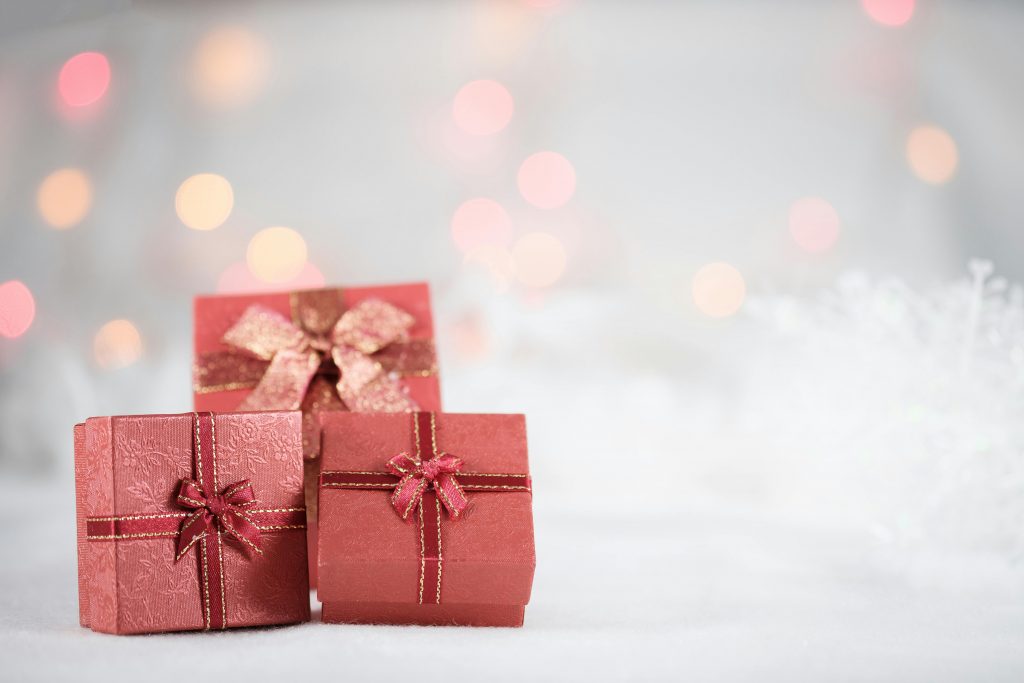 Auf einem weißen Hintergrund befinden sich drei Geschenke in rötlicher Farbe mit Schleifen drum herum.