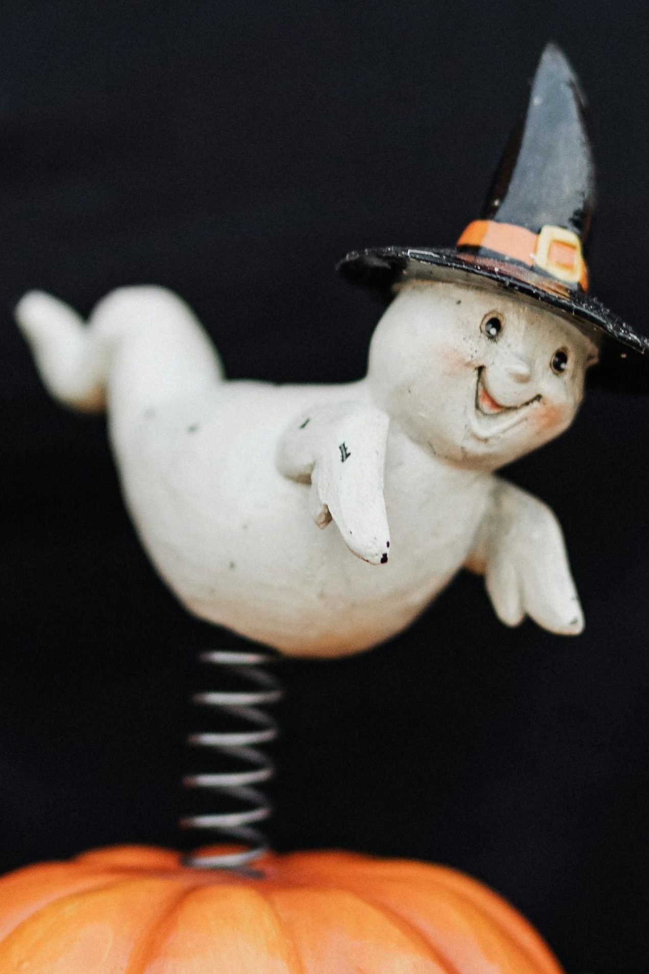 die Figur eines kleinen Gespenstes, das einen schwarzen Hexenhut mit orangem Band und goldener Schnalle trägt und sich freut