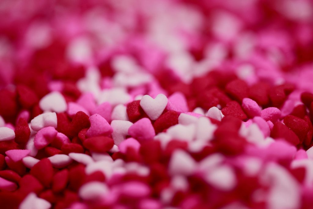 ein Haufen voller kleiner rosaner, pinker und roter Herzchen aus Filz oder Zuckerguss