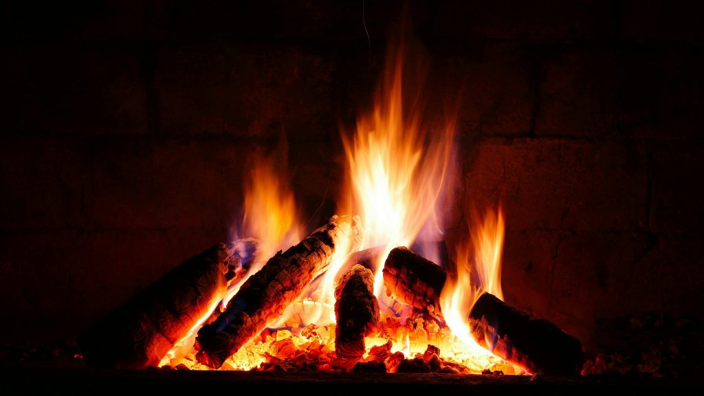 In einem Kamin prasselt eine gold-weiß-rosa-orange-rotes Feuer.